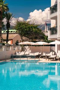 a swimming pool with lounge chairs and umbrellas at Blue Diamond Alya Hotel in Alanya
