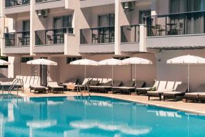 a swimming pool in front of a hotel with chairs and umbrellas at Blue Diamond Alya Hotel in Alanya