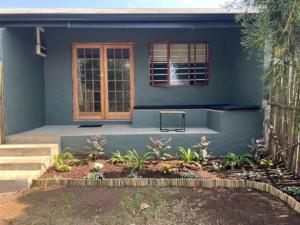 a blue house with a window and a patio at Fever Tree Self Catering in Hillcrest