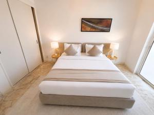 a bedroom with a large bed with two lamps at Liora Inside Al Dana beach Resort in Half Moon Bay