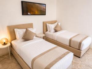 two beds in a room with a tv on the wall at Liora Inside Al Dana beach Resort in Half Moon Bay +4 photos