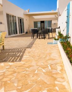 a patio with a table and chairs in a house at Liora Inside Al Dana beach Resort in Half Moon Bay