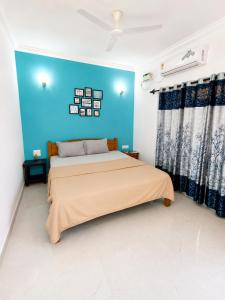 a bedroom with a bed with a blue wall at Aurevia Stays - 400m from beach in Calangute