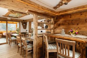 ein Esszimmer mit Holzwänden, Tischen und Stühlen in der Unterkunft Hotel Cesa Padon in Arabba