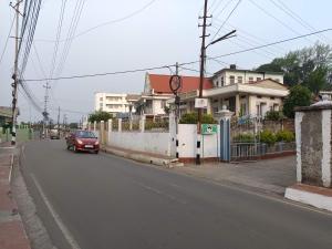 a red car driving down a street next to houses at LeeZaiah in Shillong