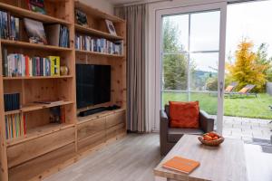 a living room with a tv and book shelves at Terrasse im Ammergau - Bad Kohlgrub in Bad Kohlgrub