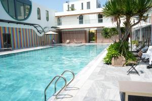a swimming pool with chairs and a building at MeySunset Hotel Phu Quoc in Phú Quốc