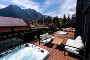 ein Whirlpool auf einer Terrasse mit Tisch und Stühlen in der Unterkunft Sky Nest Chalets in Buşteni