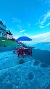 a table and chairs with an umbrella on a roof at Lemon Tree Homestay Darjeeling in Darjeeling