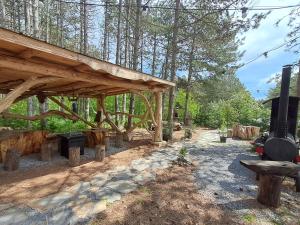 a wooden pavilion with a grill in a forest at Къща Шепотът на бора in Varna City