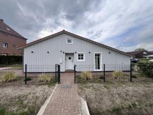 a white building with a fence in front of it at Wooden Silence - Wo Ruhe zuhause ist in Soltau