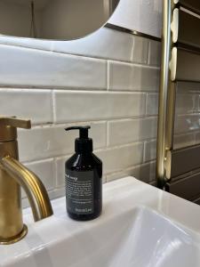 a black bottle of soap sitting on a bathroom sink at Wooden Silence - Wo Ruhe zuhause ist in Soltau +41 photos