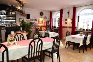 a restaurant with tables and chairs with pink and white tablecloths at Eden Panzió in Eger