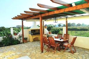 a patio with a table and chairs and a fireplace at Voula Accommodation in Agios Georgios