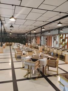 an empty restaurant with tables and chairs and lights at The Green Shadow Business Hotel in Chittagong