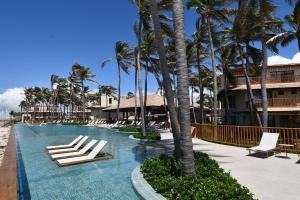 a swimming pool with lounge chairs and palm trees at Casa Baião in Fortim