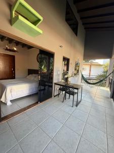 a bedroom with a bed and a table on a tiled floor at Pousada Bahan Suites privativas - ideal para Casais in Ubatuba