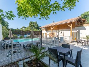 a patio with a table and chairs next to a pool at Vacancéole - Les Rives du Lac in Lacanau