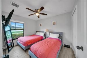 a bedroom with two beds and a ceiling fan at Southwest Florida Paradise in Cape Coral