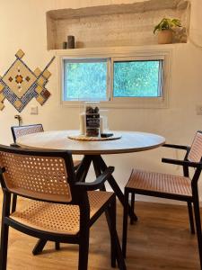 a table and chairs in a room with two windows at צימרים בצפון - אדם אדמה in Sheʼar Yashuv +13 photos