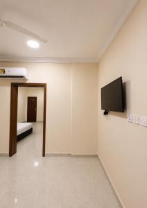 a room with a tv on the wall and a bed at RED Bn Saif in Salalah