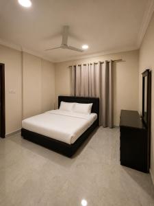 a bedroom with a white bed and a night stand at RED Bn Saif in Salalah