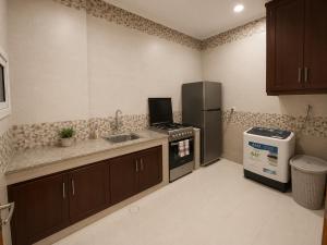a kitchen with a stove and a sink and a refrigerator at RED Bn Saif in Salalah