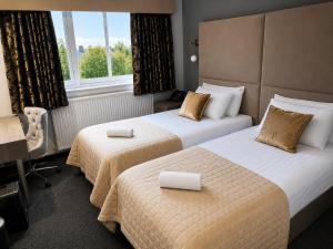 a hotel room with two beds and a window at The Popinjay Hotel in Larkhall