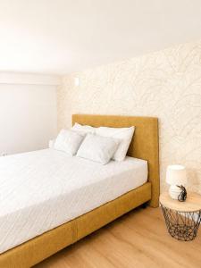 a bedroom with a bed with white sheets and a table at Casa Trainêra in Nazaré