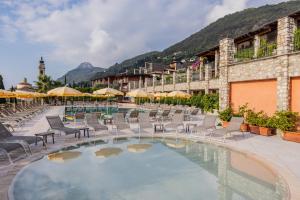 a resort with a pool with chairs and umbrellas at Residence Borgo Dei Limoni - Appartamenti con Garage in Gargnano