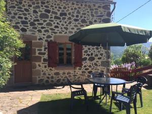 a table with chairs and an umbrella in front of a building at Gite Les Bannes in Saint-Sauves- dʼAuvergne
