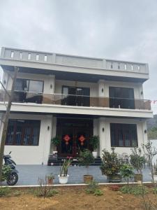 a white house with a balcony and a motorcycle in front at Dũng Đậu Homestay in Hai Phong