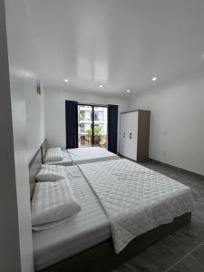 a white bedroom with two beds and a window at Dũng Đậu Homestay in Hai Phong