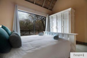 a bedroom with a large bed with a large window at Majolie, Private Pool, Look Out Tower in Marloth Park