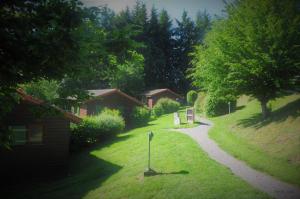 a path through a yard with houses and trees at Les Noës - Parc des chalets in Saint-Rirand