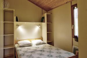 a small bedroom with a bed and shelves at Les Noës - Parc des chalets in Saint-Rirand