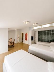 a white bedroom with two beds and a chair at Kein Hotel in Durrës