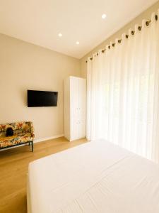 a bedroom with a white bed and a tv at Kein Hotel in Durrës +12 photos
