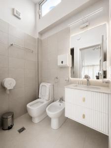 a white bathroom with a toilet and a sink at Kein Hotel in Durrës