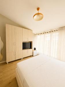 a white bedroom with a large bed and a television at Kein Hotel in Durrës