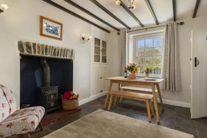 a living room with a table and a wood stove at Manteg - quaint holiday cottage by the sea with direct beach access in Aber-Arth +29 photos