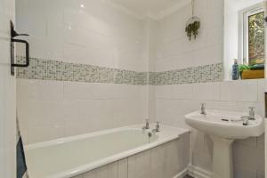 a white bathroom with a tub and a sink at Manteg - quaint holiday cottage by the sea with direct beach access in Aber-Arth