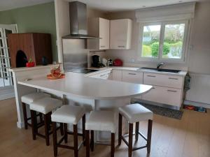 a kitchen with a large white table and stools at Maison confortable à Verdun avec jardin in Verdun-sur-Meuse