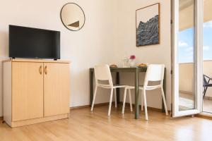 a dining room with a table with chairs and a television at Dana Apartments - Seafront Pašman in Pašman
