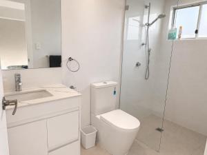 a white bathroom with a toilet and a shower at 19 Pimpama Home in Pimpama +5 photos