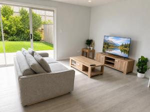 a living room with a couch and a flat screen tv at 19 Pimpama Home in Pimpama