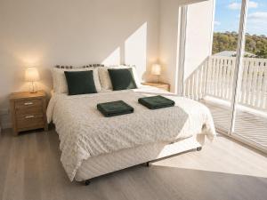 a bedroom with a bed with two green towels on it at 19 Pimpama Home in Pimpama