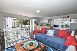 a living room with a blue couch with red pillows at Voetjieshang in Yzerfontein