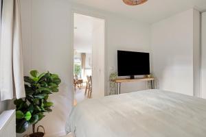 a white bedroom with a bed and a flat screen tv at Knusse Tiny house op de Veluwe in Epe +18 photos