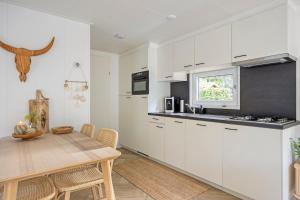 a kitchen with white cabinets and a wooden table at Knusse Tiny house op de Veluwe in Epe